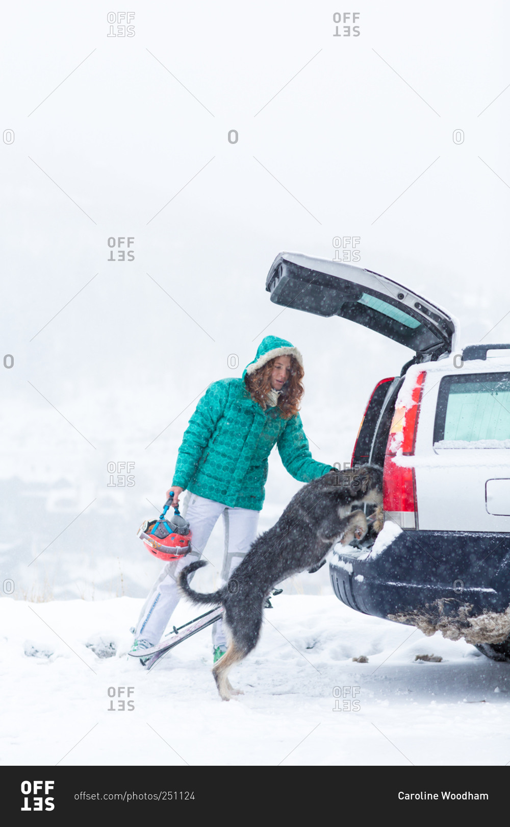 Skier with her dog at vehicle in snowstorm
