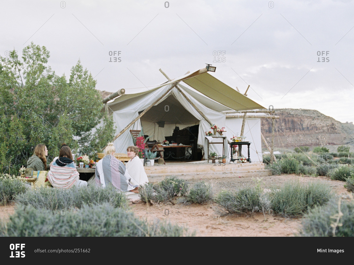 Group of women enjoying an outdoor meal in a desert by a large tent