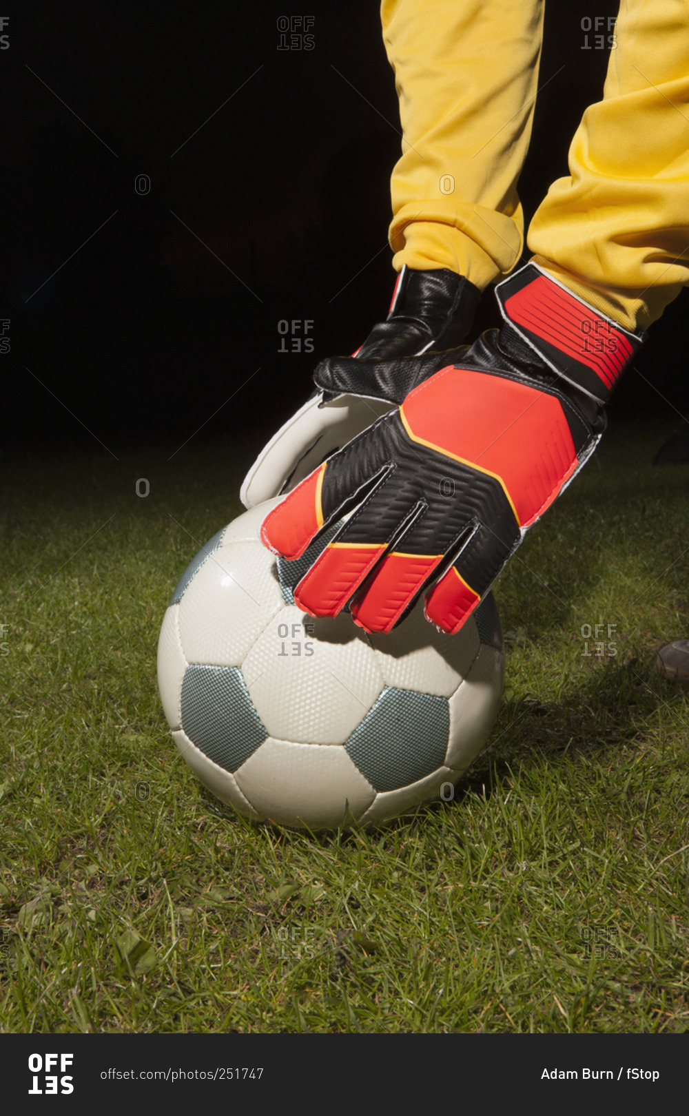 Young male goalie placing soccer ball on field