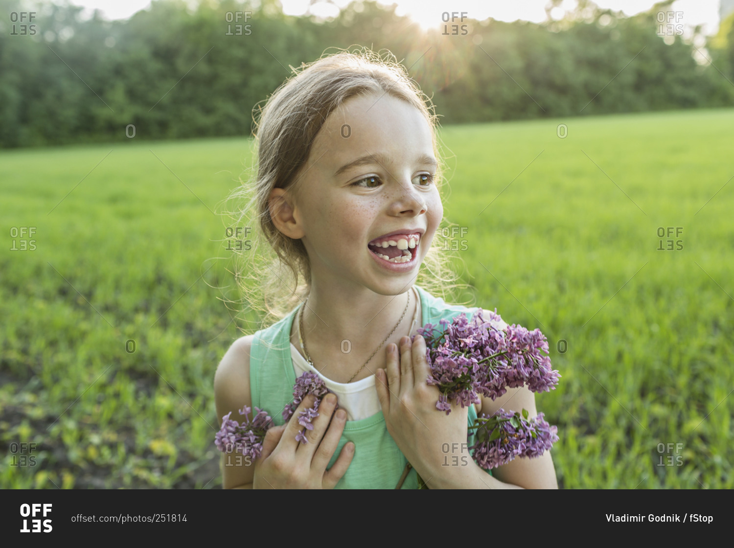 Cheerful girl holding purple flowers on field