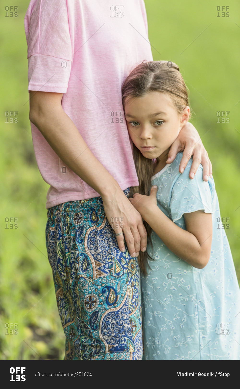 Sad girl hugging mother on field