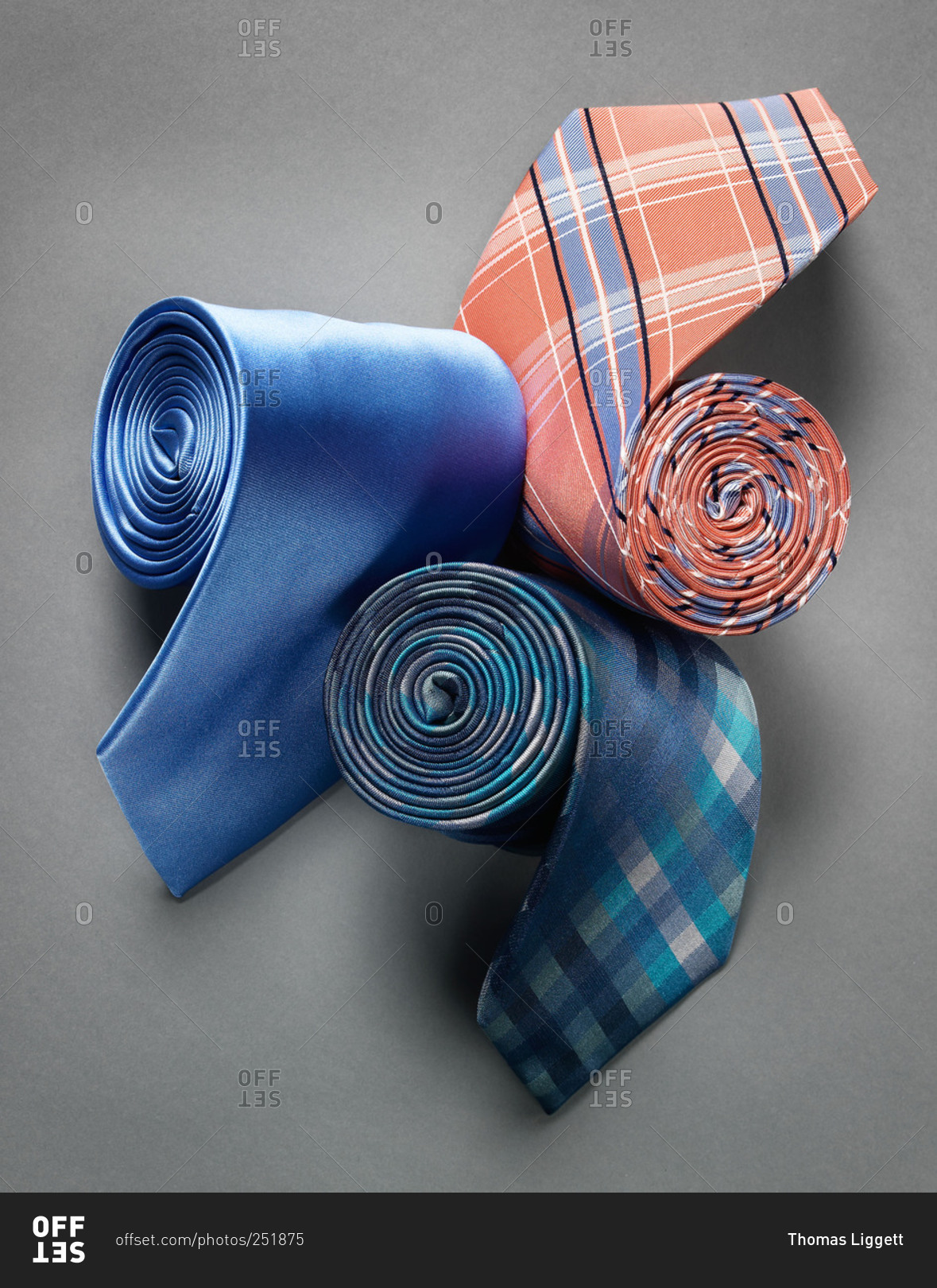 Three rolled silk neckties on white background stock photo - OFFSET