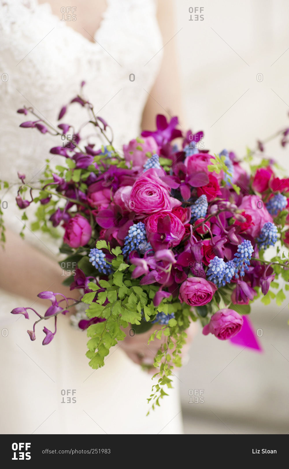 A bride holds her bouquet of bright purple flowers