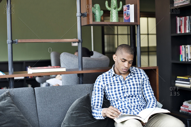 Young man reading a book in a bookstore