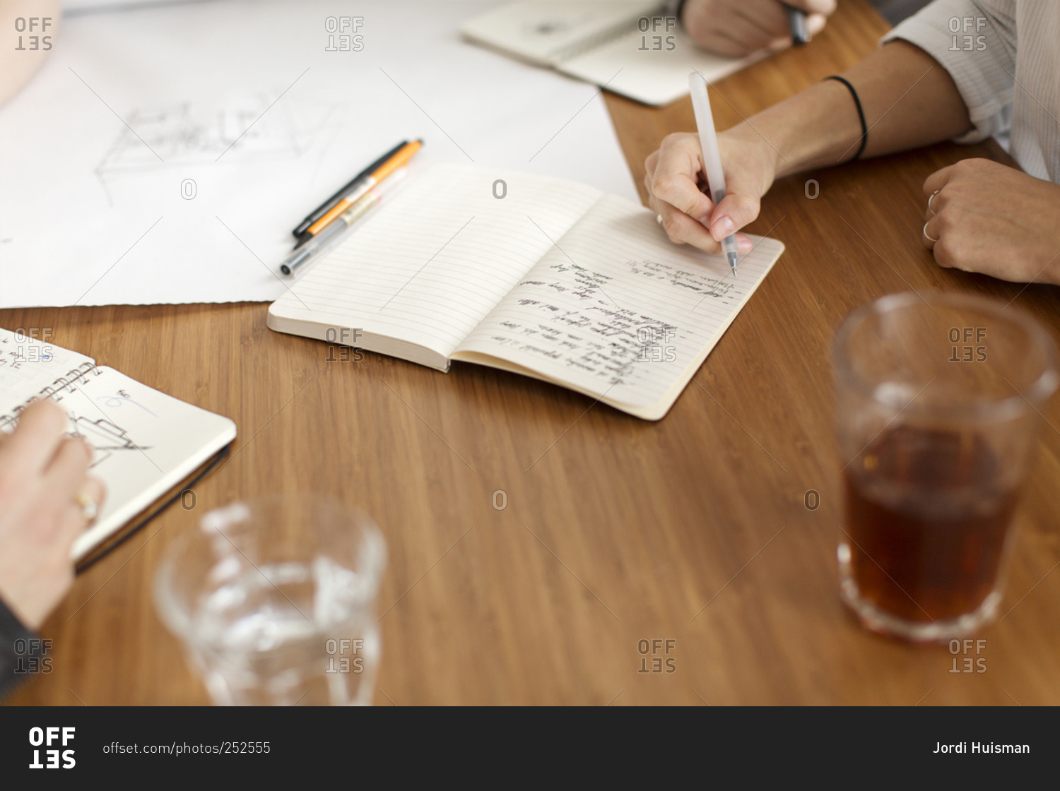 Four people taking notes and drawing during meeting