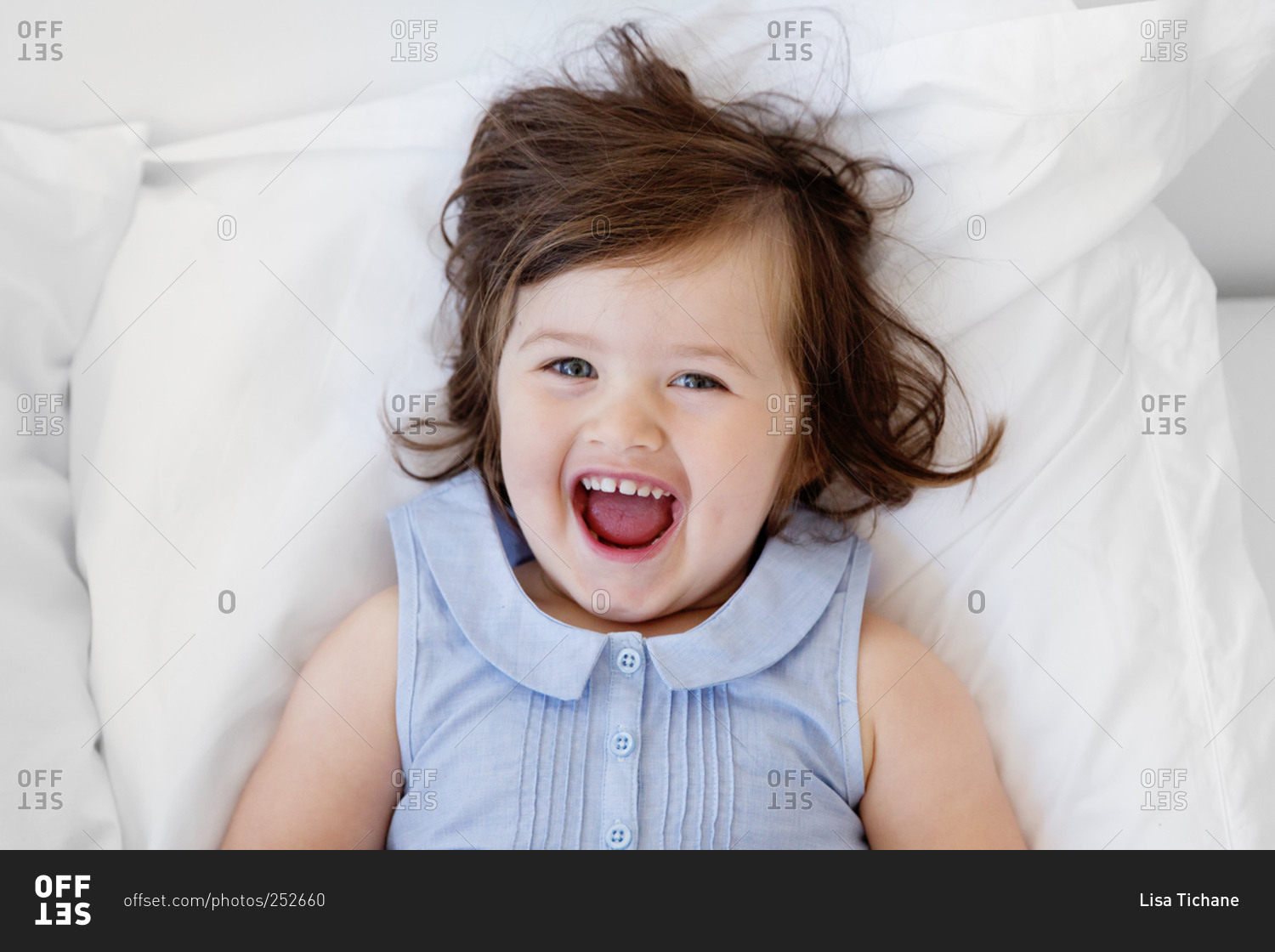 Happy little girl lying on a bed