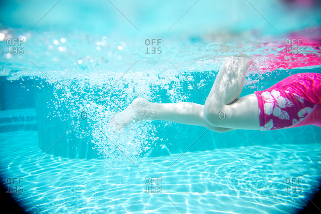 Underwater view of a girl swimming stock photo - OFFSET