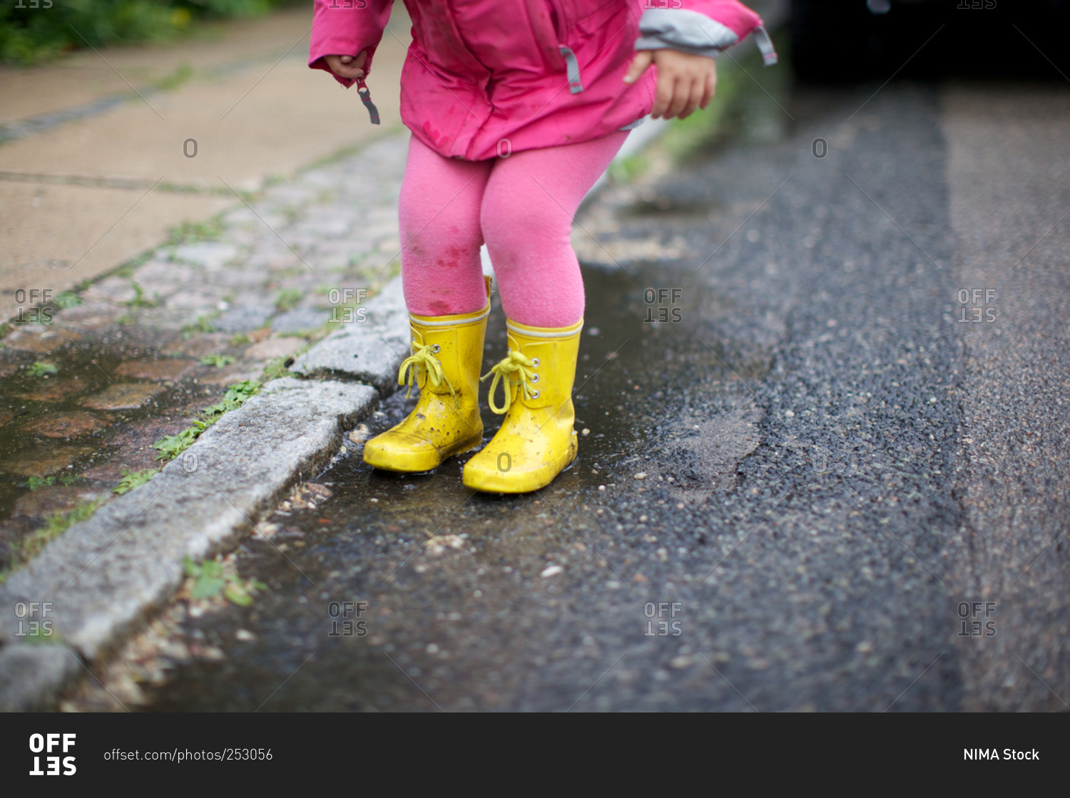 A girl in rain boots at roadside