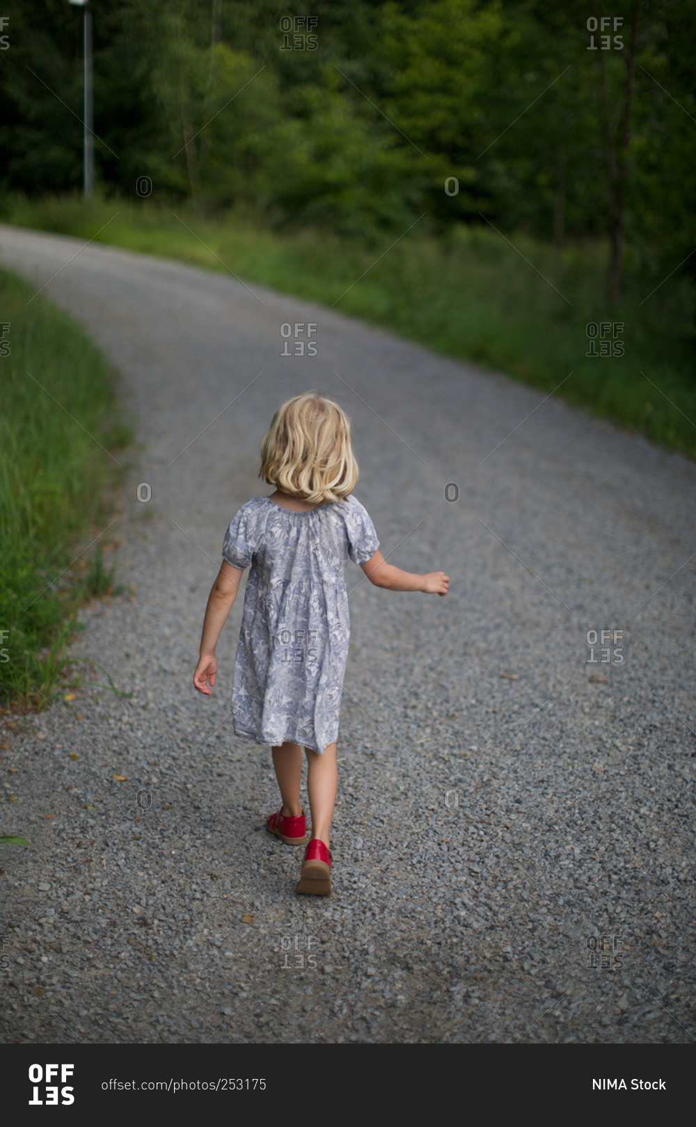 Girl walking alone on gravel road stock photo OFFSET