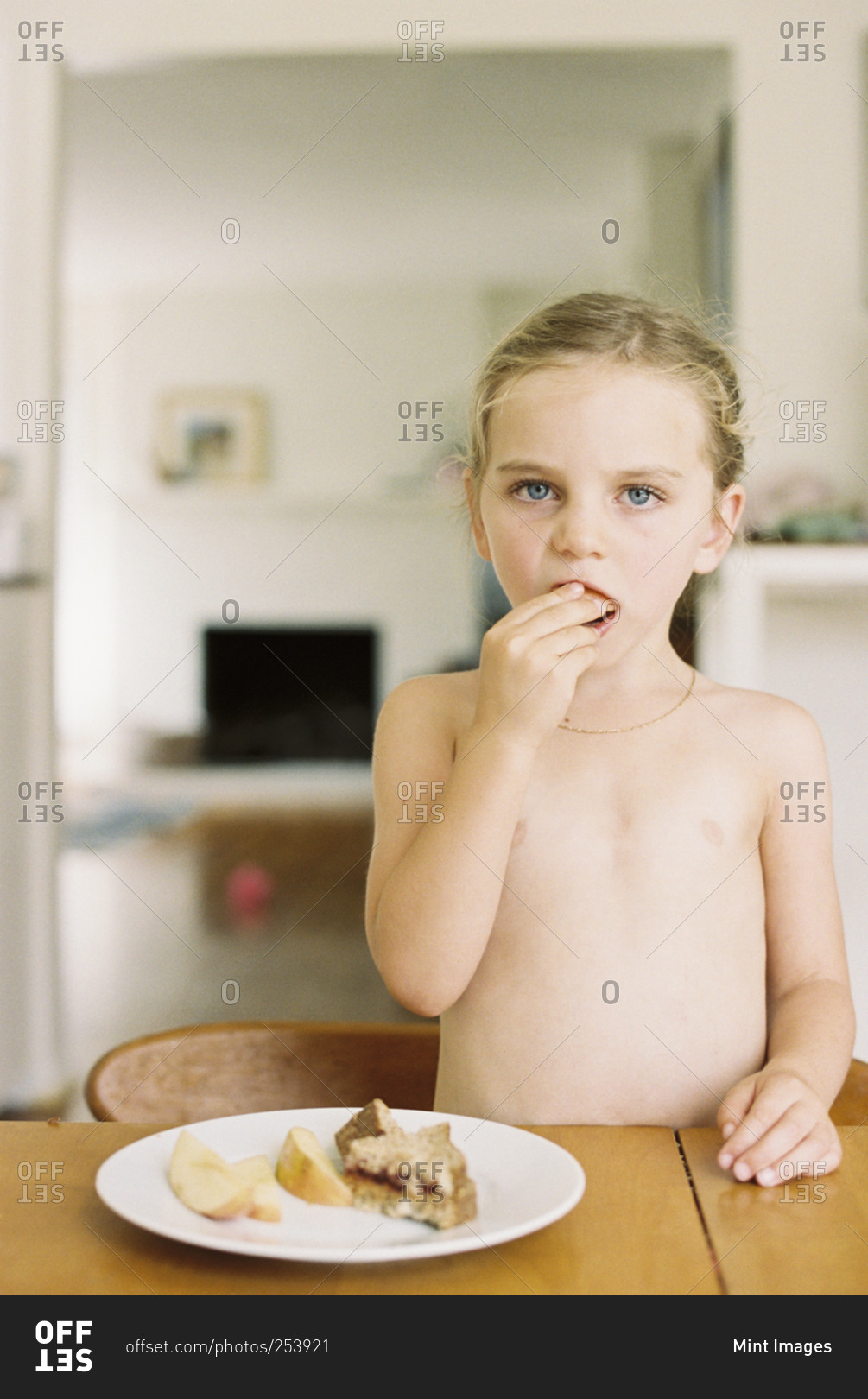Nude Young Girl Standing At A Table Eating A Sandwich And A