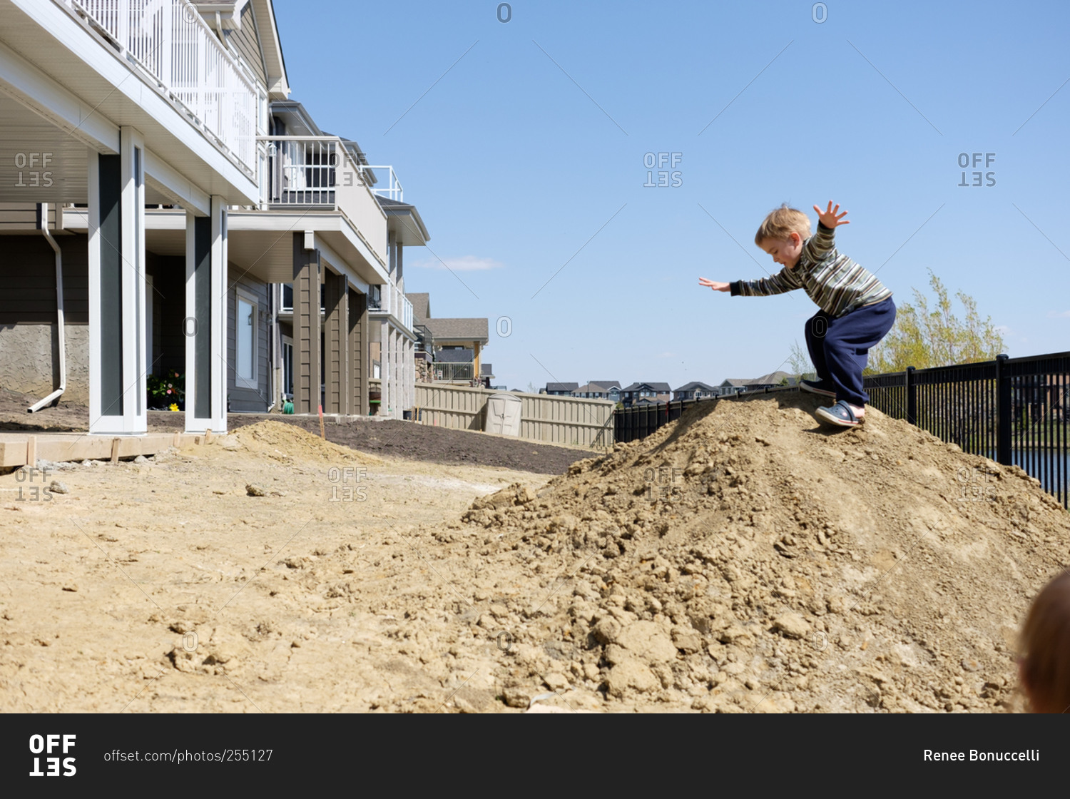 Little boy playing on dirt pile in backyard