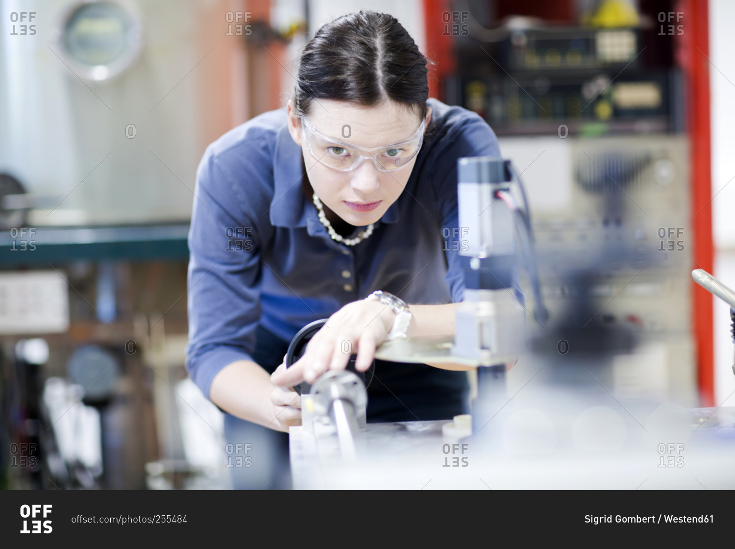 Young woman with safety goggles working at machine