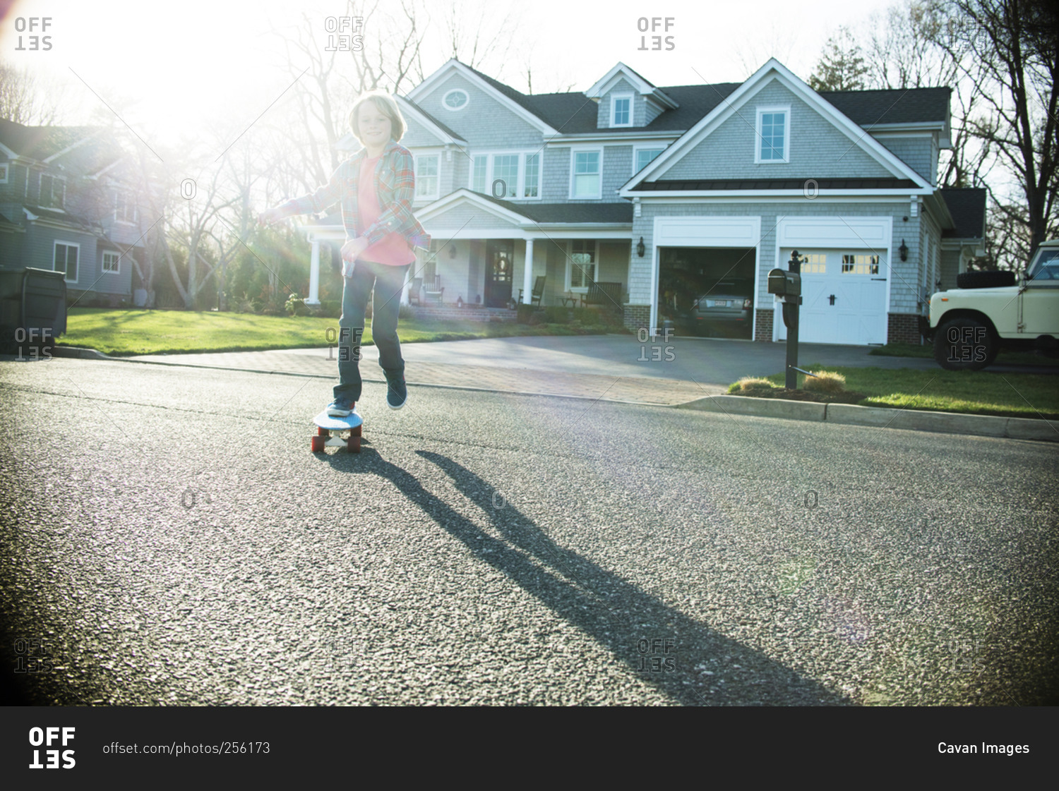 Boy riding skateboard in street in sunlight