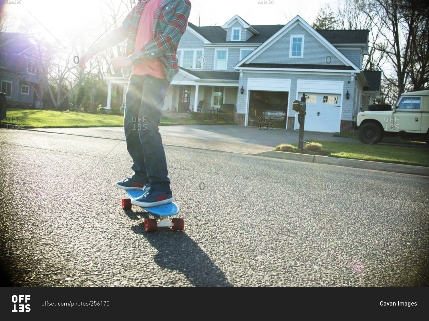 Boy riding a skateboard in street in sunlight