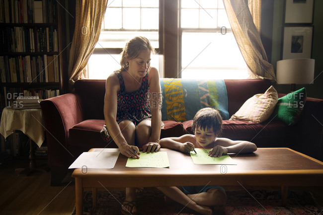 Woman teaching young boy to draw letters