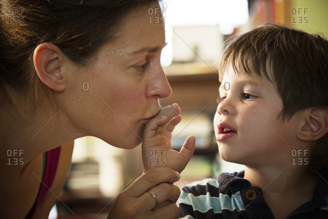 Mom kissing boy's bandaged finger
