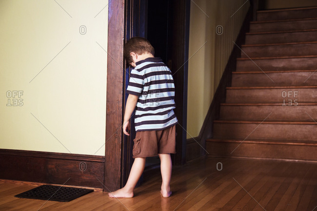 Boy standing leaning head on doorframe