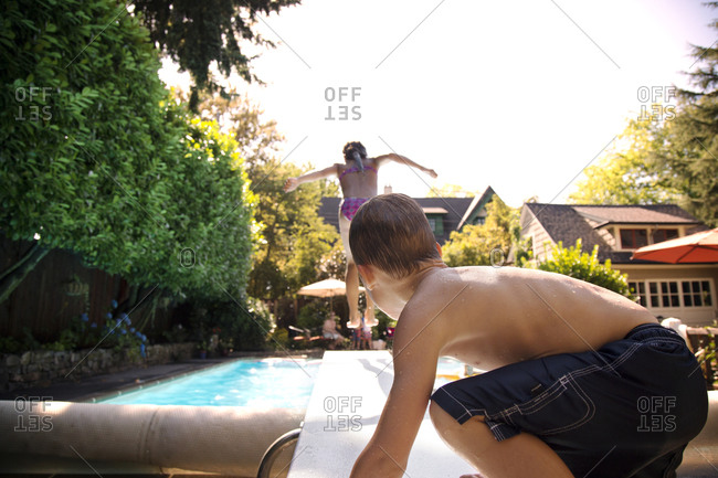 Boy watching a girl dive into swimming pool