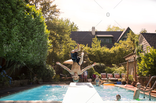 Boy mid flip jumping into swimming pool