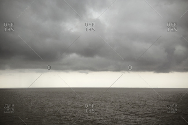 Still ocean water under rain clouds