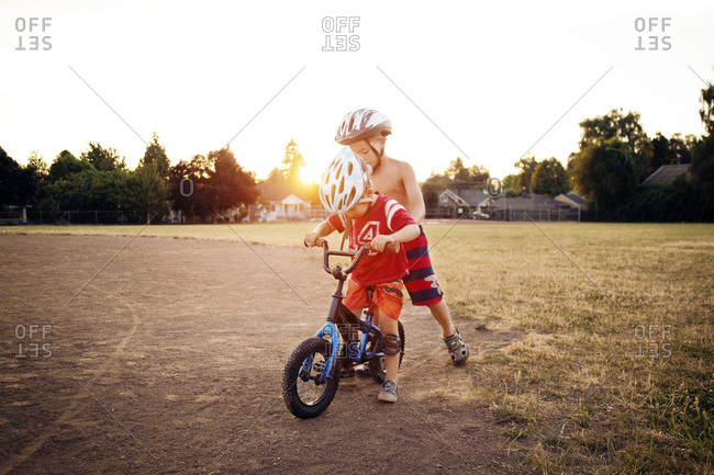 Boy helping another to ride his bike