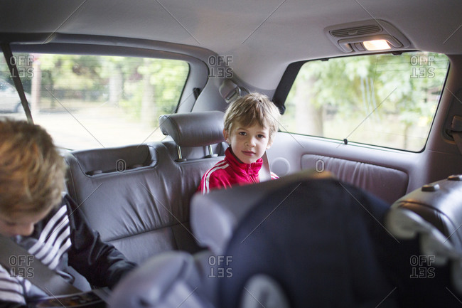 Little boy sitting calmly in back seat by brother