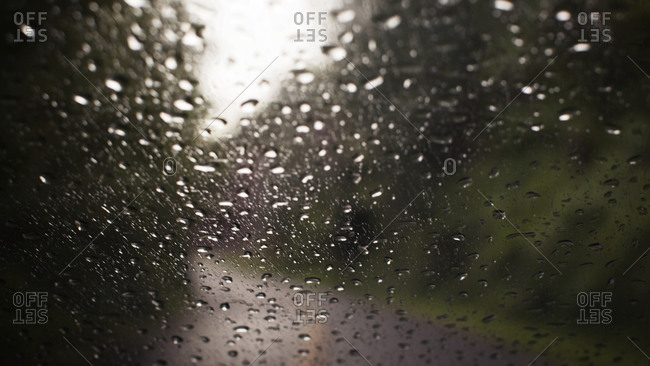 Rain obscuring rural view through a windshield