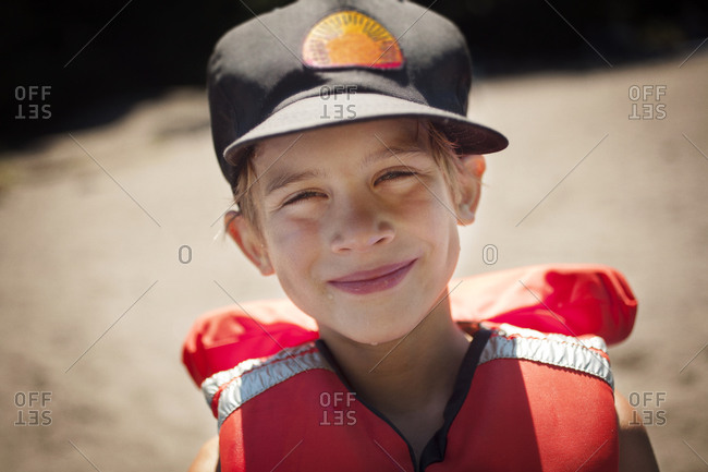 Portrait of boy smiling in baseball cap and life vest
