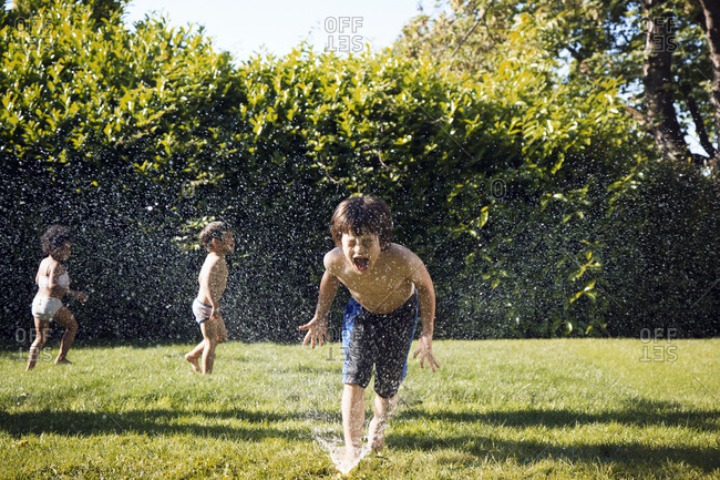Boy putting face into water from sprinkler