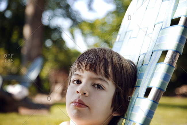 Portrait of boy sitting in lawn chair in summer