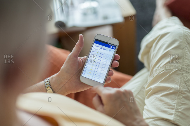 Senior woman looking at weather forecast on smartphone display