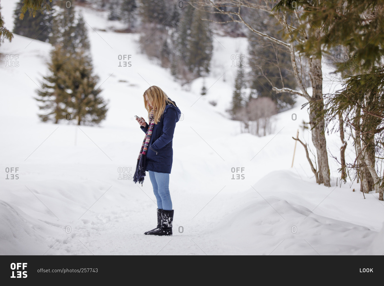Young woman checking her smart phone in the winter
