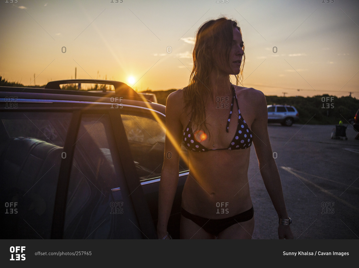 Woman standing at her open car at a beach access