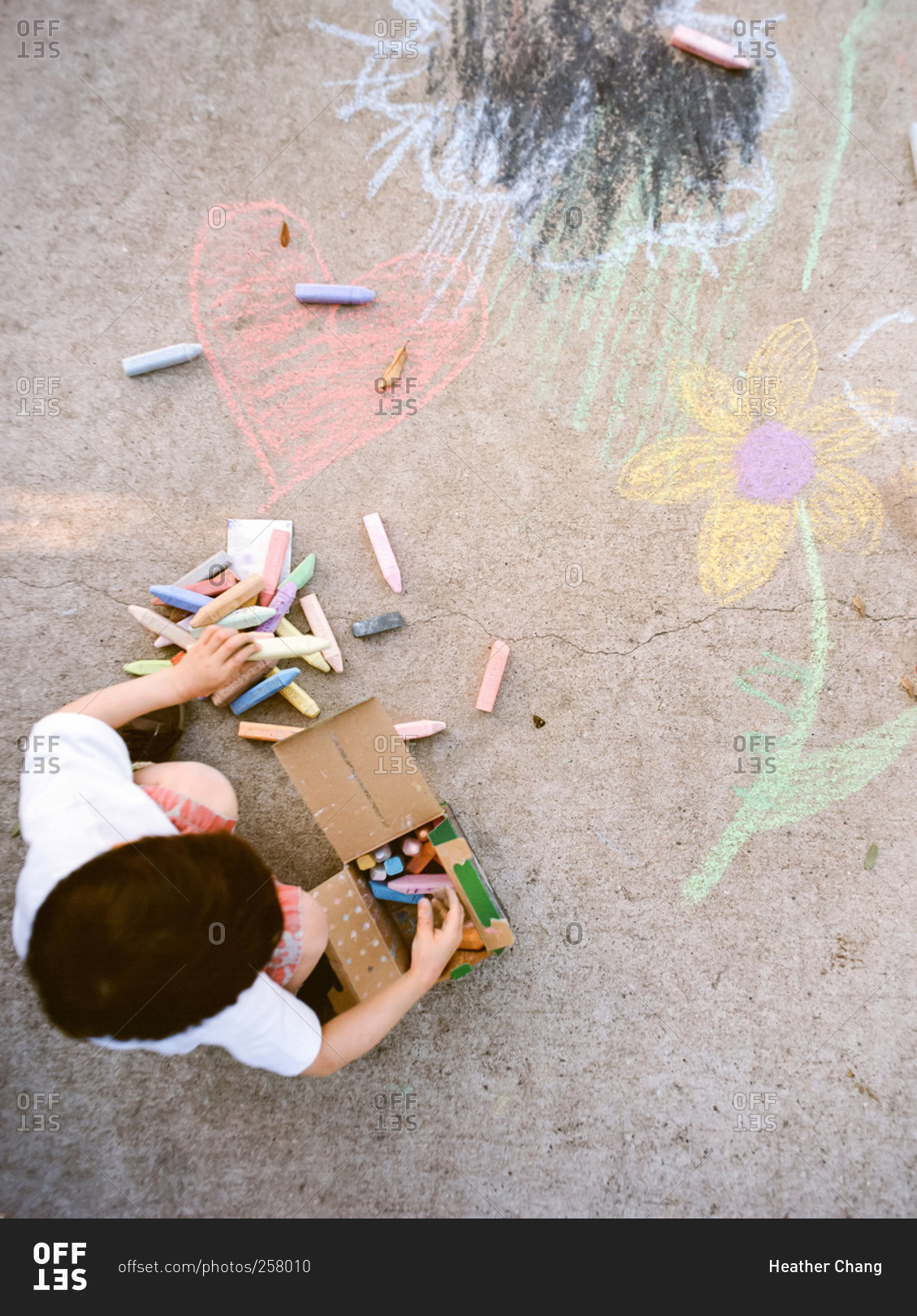 Overhead view of young boy drawing with sidewalk chalk