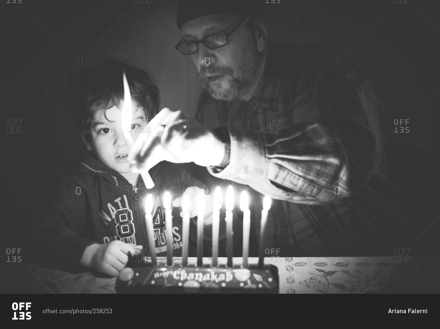 Child and grandfather lighting Hanukkah candles
