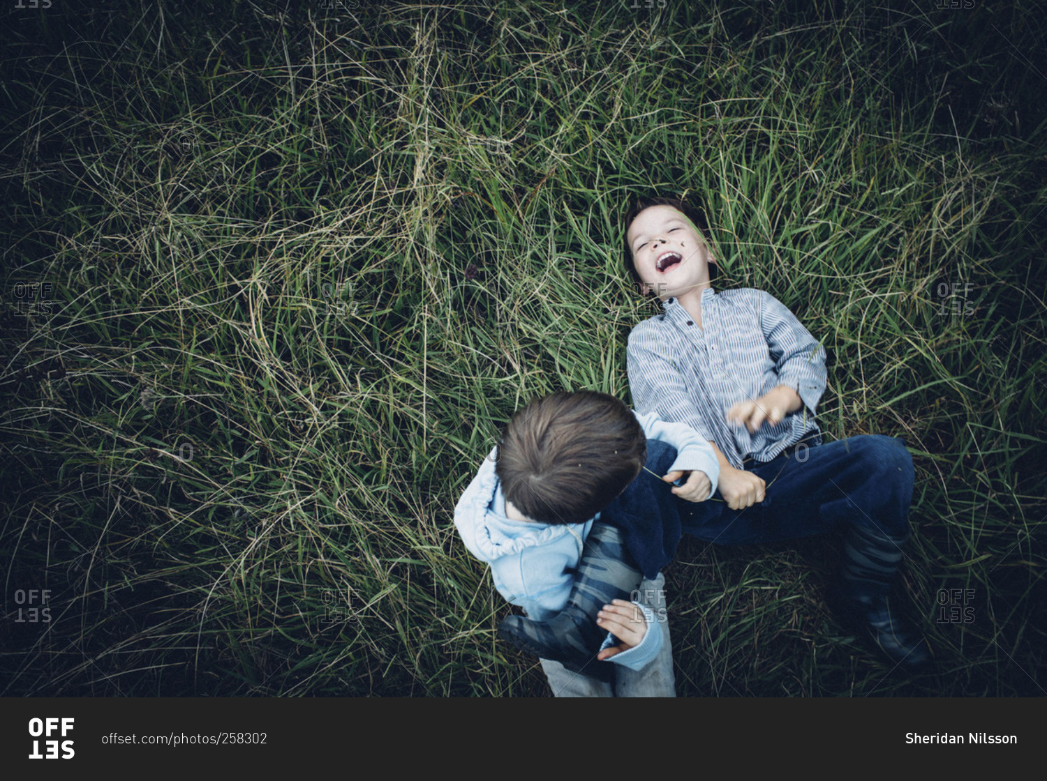 Two boys wrestling and laughing in field