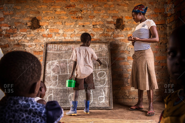 Paicho, Uganda - March 4, 2015: Boy standing at a classroom chalkboard pointing to letters