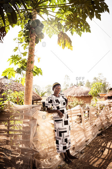 Lacor, Uganda - March 5, 2015: Woman leaning against a fence under a palm tree