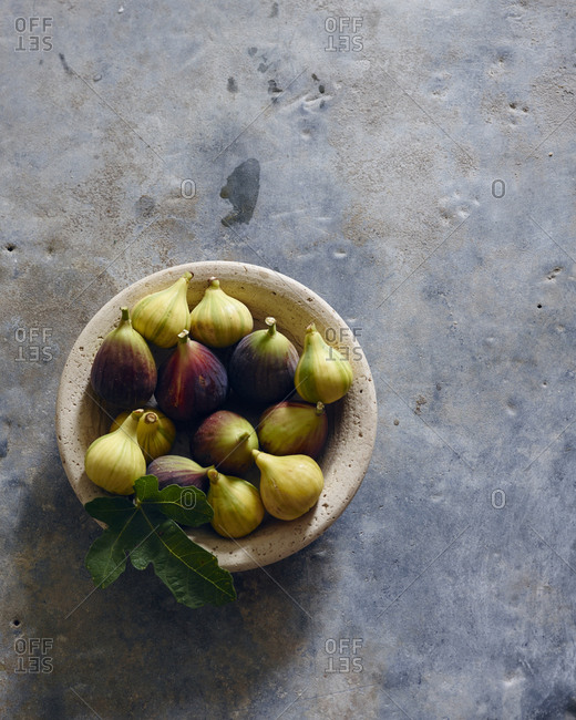 Overhead view of fresh figs in a bowl with a fig leaf