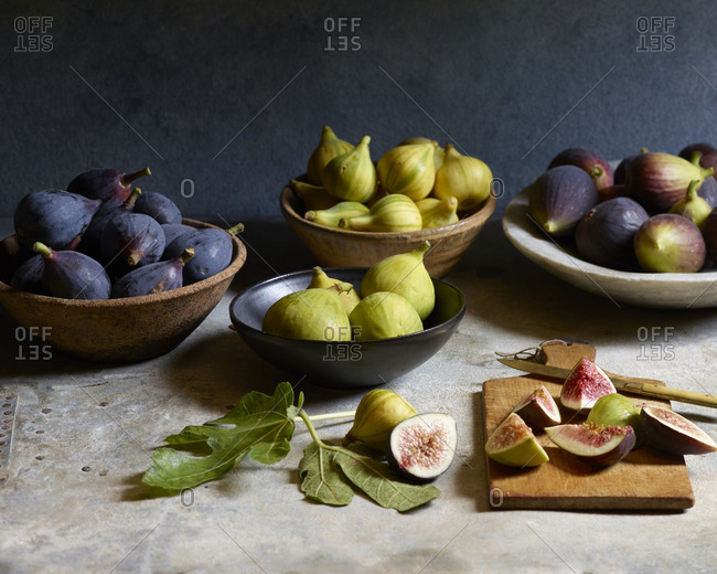 Still life of fresh figs in bowls with sliced figs on cutting board