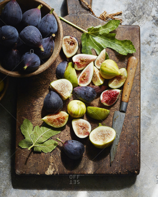 Overhead view of sliced figs on cutting board with whole figs in bowls