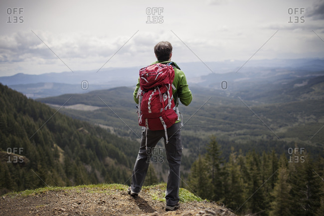 Man in backpack looking over expansive mountain valley