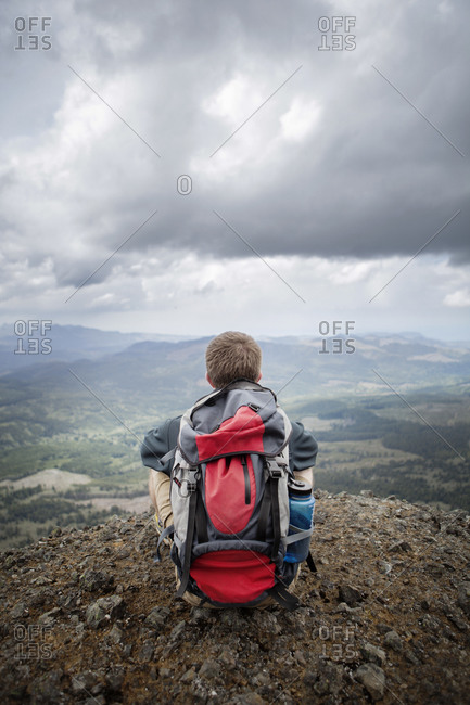 Man in backpack looking at expansive mountain valley