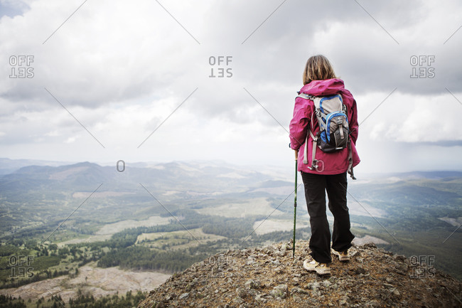 Woman in backpack looking over expansive mountain valley