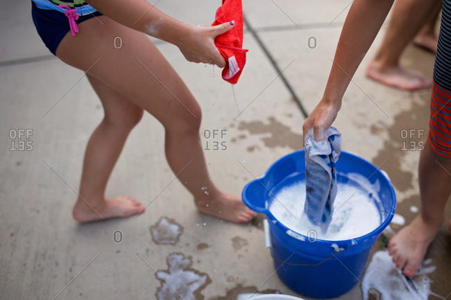 Kids pulling soapy washcloths from a bucket while washing a car