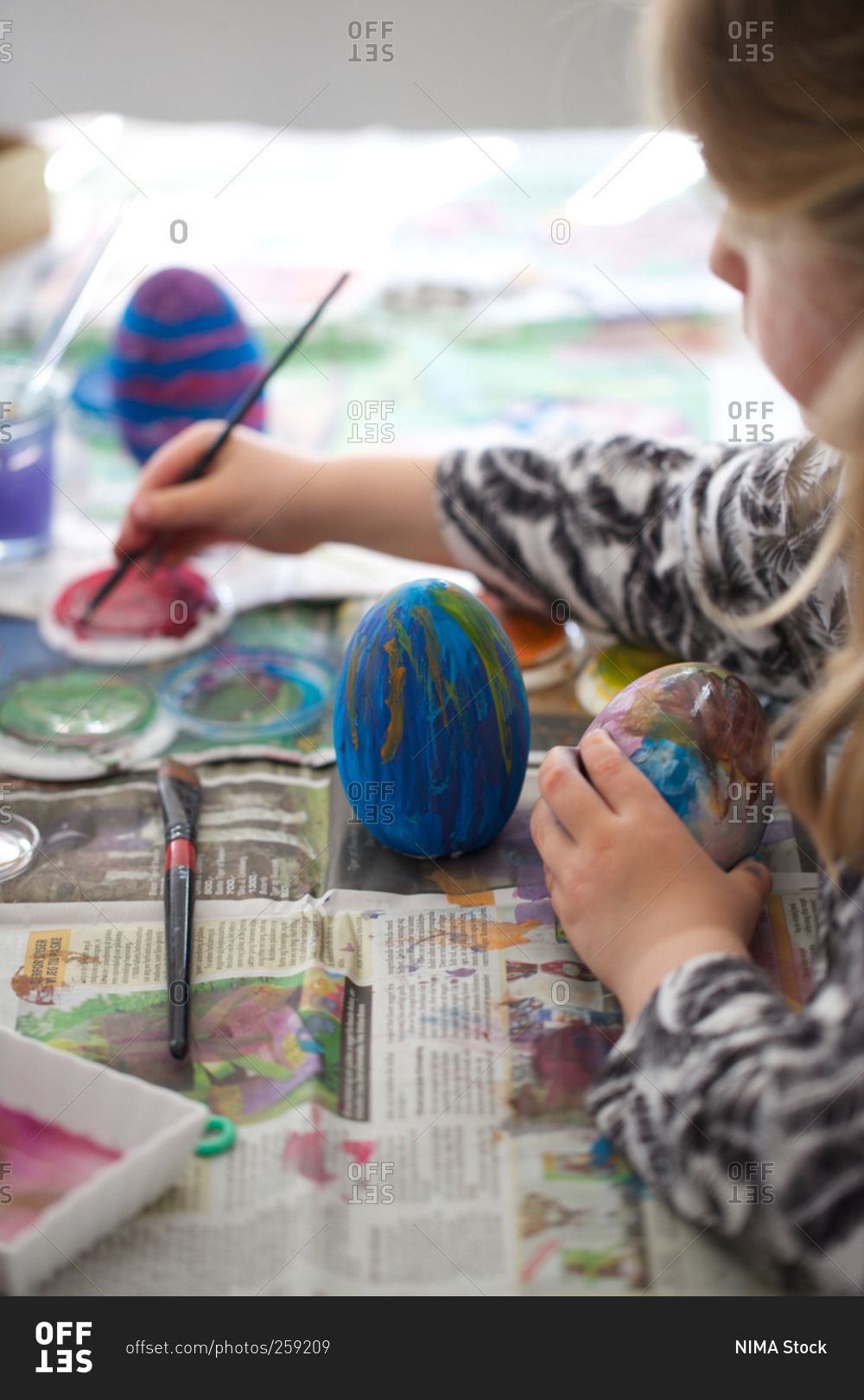 Girl coloring Easter eggs paintbrush