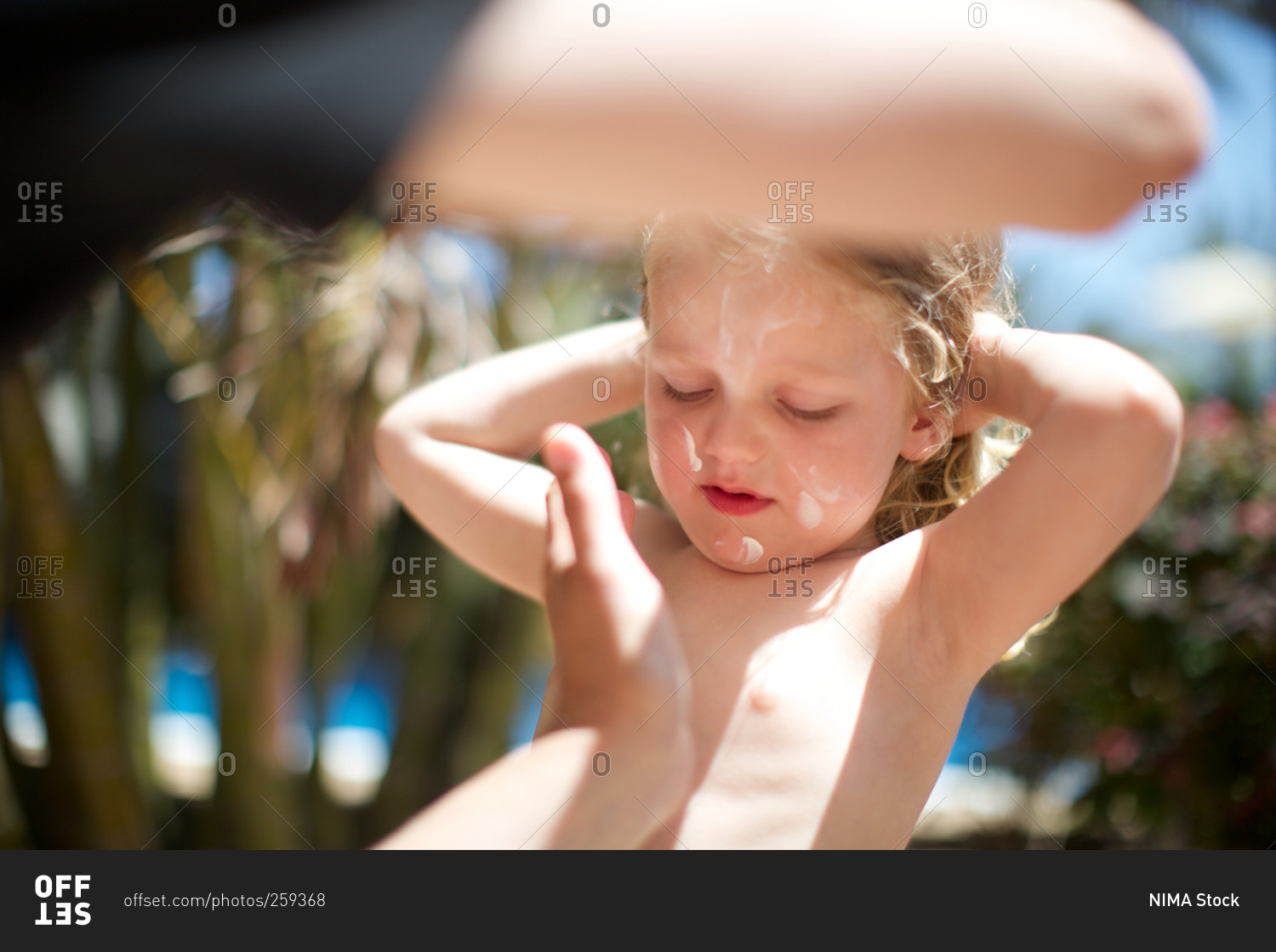 Parent applying sun lotion on girl's face