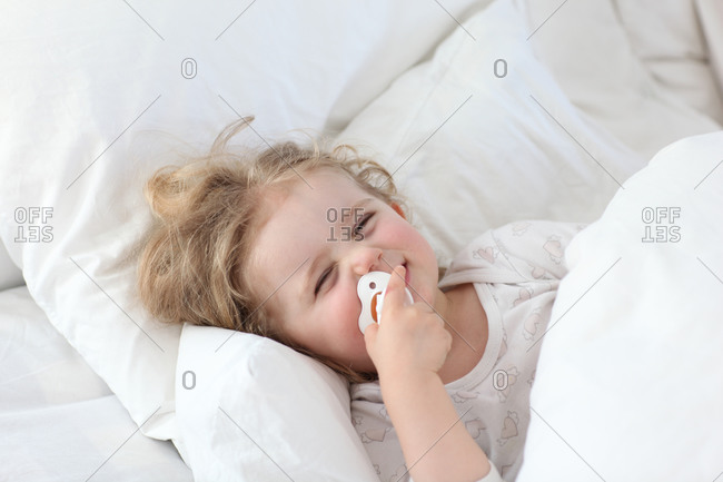 Charming blond girl with curly hair waking up happy
