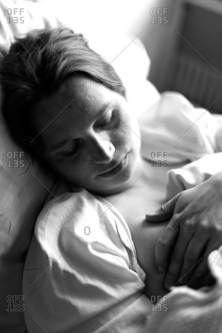 Mother nursing her newborn baby in hospital bed