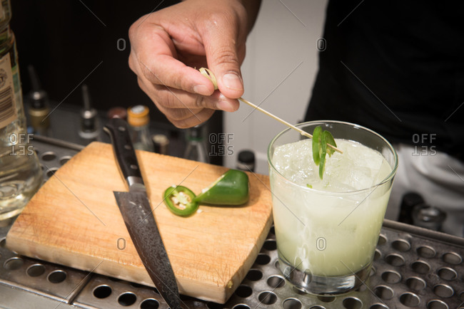 Bartender garnishing a cocktail with jalapeno